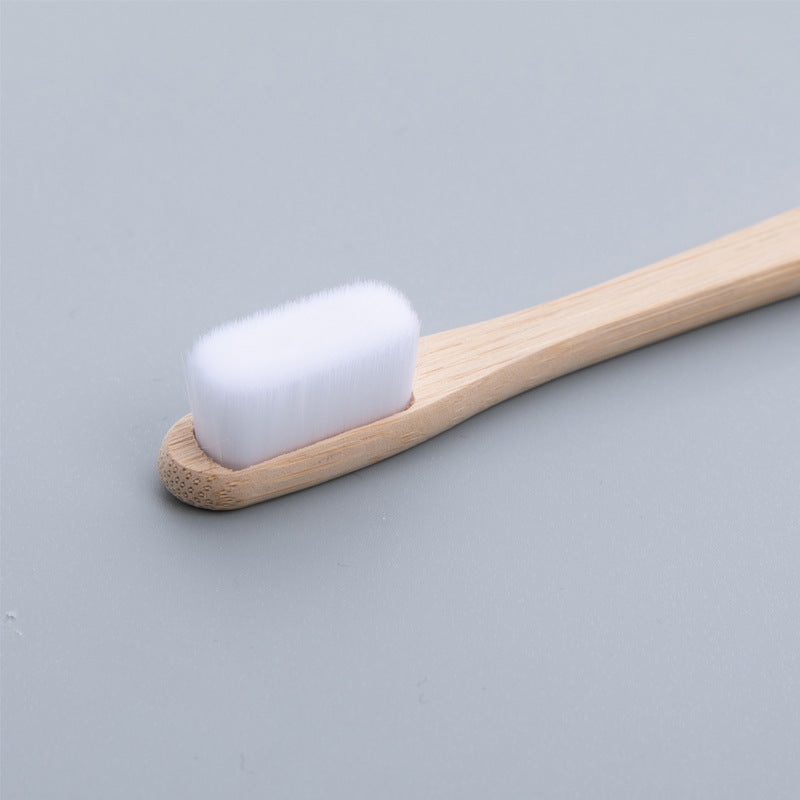 Bamboo toothbrush with white bristles on a gray background