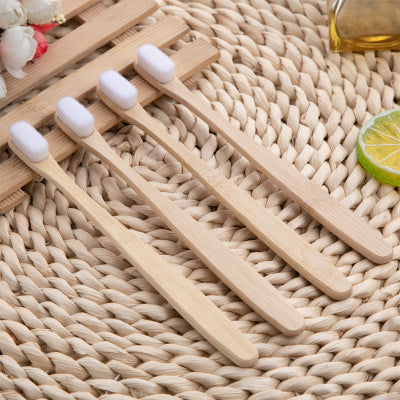 Set of wooden toothbrushes with white bristles on a woven surface.